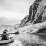 Woman in a kayak on the river between the mountains